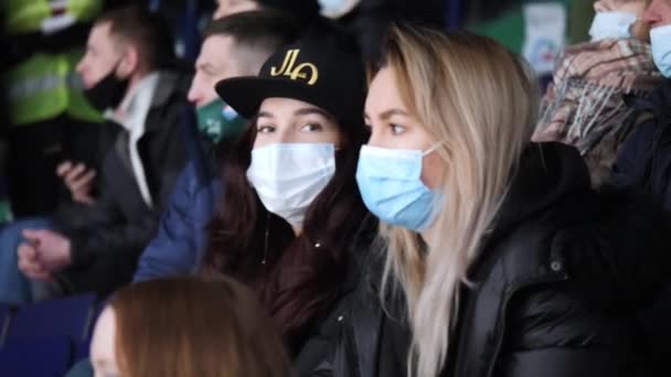 Jovens mulheres com máscaras médicas assistir jogo de hóquei no estádio — Vídeo de Stock