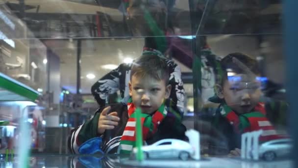 Little boy with scarf points to cute toy car on display — Stock Video