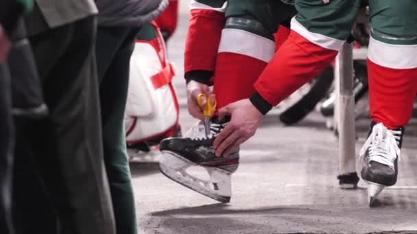 Хоккеист режет шнурки на ботинках, готовясь к игре — стоковое видео