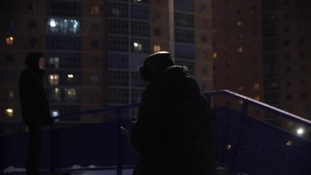 コートを着た男と帽子は冬に街の通りに2階に行きます — ストック動画