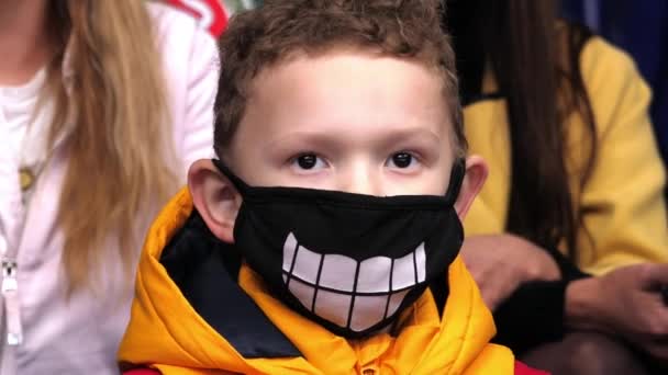 Ragazzino con sorriso sulla maschera medica guarda partita di hockey — Video Stock