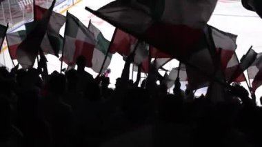 Hokey kulübü hayranları siluetleri seyircilerin önünde bayrak sallıyor.