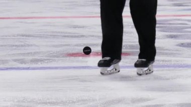 Hokey hakemi buz pistinden diski almak için eğildi.