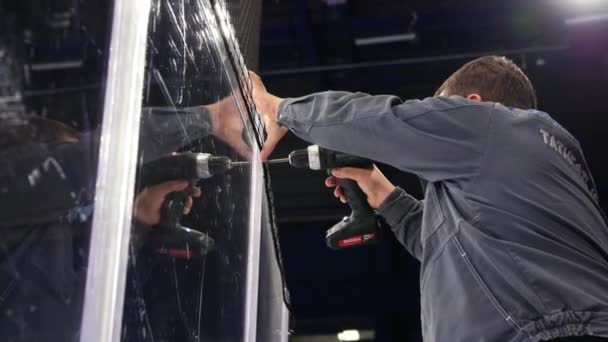 Employee in grey uniform assembles shield on ice arena — Stock Video