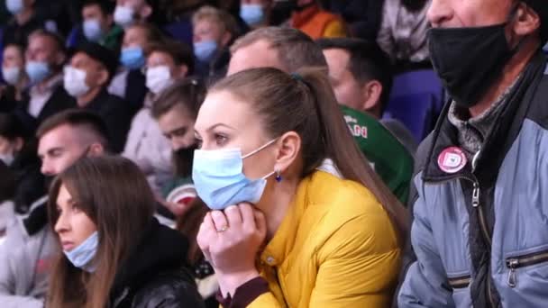 Woman with ponytail and mask watches play of hockey teams — Stock Video