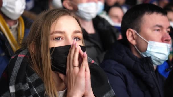 Langhaarige Frau mit medizinischer Maske verfolgt Länderspiel — Stockvideo