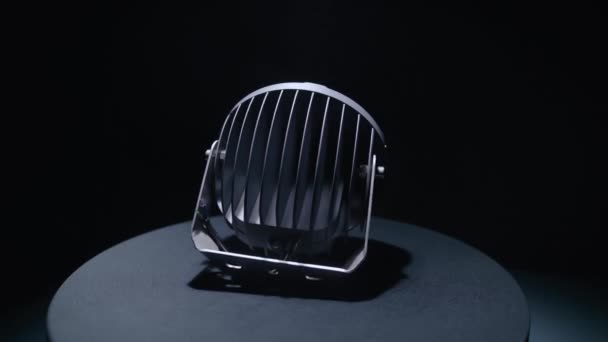 Okrągły projektor LED obraca się na stojaku w ciemnym studio — Wideo stockowe
