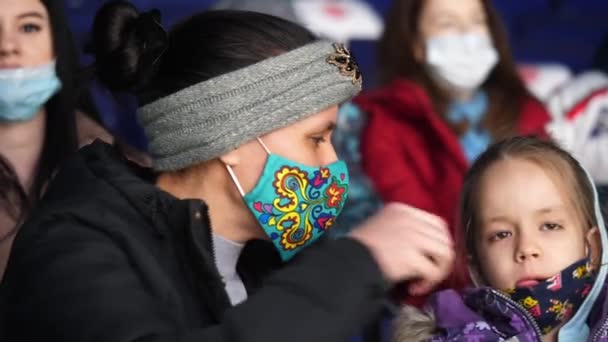 Мама настраивает маску маленькой дочери на хоккейном матче — стоковое видео