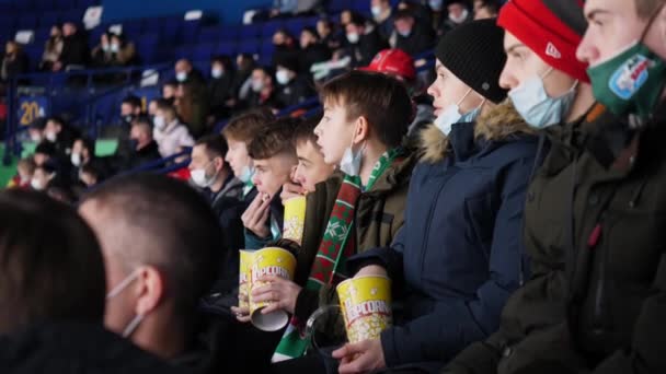 Teenage boys eat popcorn watching hockey game at stadium — Stock Video
