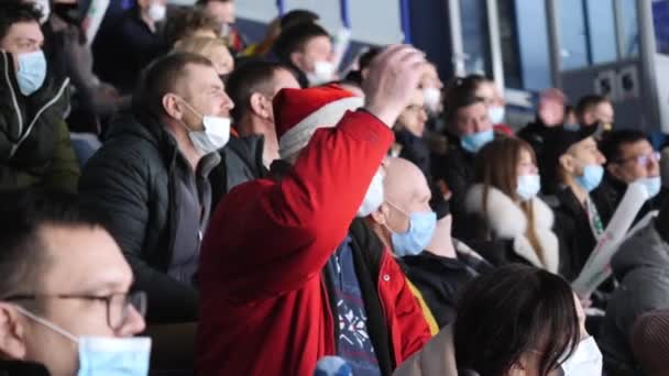 Uomo anziano a Babbo Natale cappello orologi hockey allo stadio — Video Stock