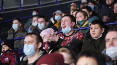 Maskeli duygusal adam stadyumda hokey oyuncusunu destekliyor.