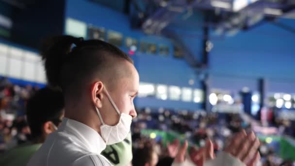 Молодые и старшие зрители смотрят хоккейный матч на стадионе — стоковое видео