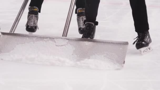 Рабочие чистят лёд лопатами, катаясь на коньках вдоль катка в хоккее — стоковое видео