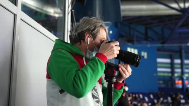 Фотограф фотографирует хоккейный матч на ледовой арене — стоковое видео