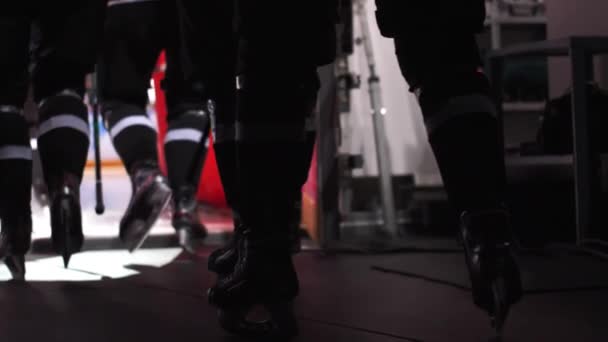 Мужская команда хоккеистов с коньками бежит по темному залу — стоковое видео