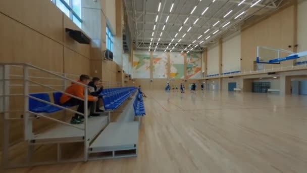 Děti hrají basketbal pod vedením učitele v tělocvičně — Stock video