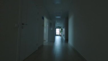 Tıbbi bürolara giden yarı karanlık koridor boyunca hareket