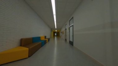 Okulun duvarlarında resimler olan koridorlar boyunca hızlı hareket