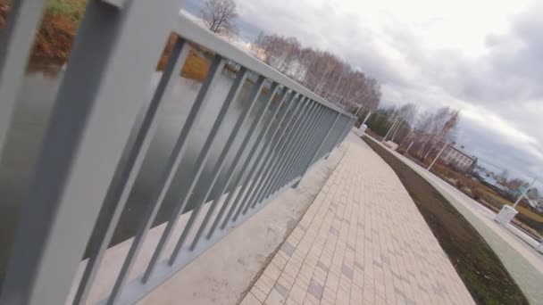 Grey railing on paved embankment in young autumn park — Stock Video