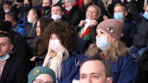 Молодые женщины в теплой одежде в масках смотрят хоккей — стоковое видео
