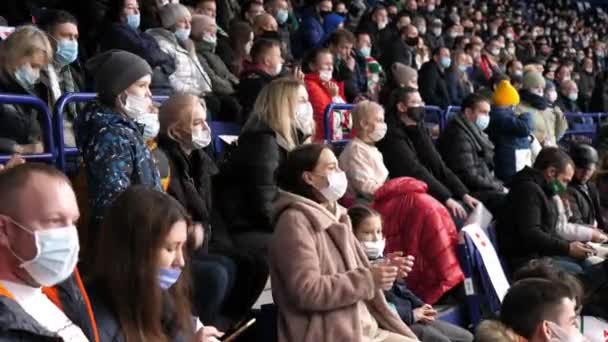 Толпа фанатов спорта в масках поддерживает местную хоккейную команду — стоковое видео