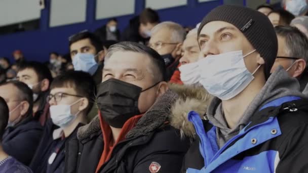 Hombres mayores y jóvenes con máscaras ven hockey en el estadio — Vídeo de stock