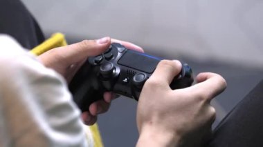 Genç adam video oyunu oynuyor. Odasında joystick dinleniyor.