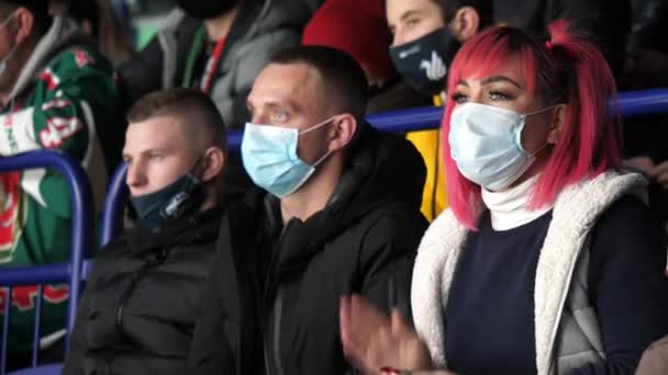 Woman with mask and pink hair claps hands at hockey game — Stock Video