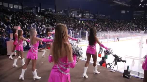 Cheerleaders in openhartige roze pakken heffen pompons op bij hockey — Stockvideo