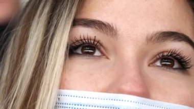 Maskeli ve kahverengi gözlü sarışın kadın hokey seyrediyor.