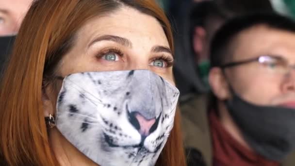 Зрелая женщина с пантерной мордой на маске смотрит хоккей — стоковое видео