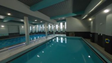 Modern spor merkezi binasının yakınındaki temiz su ve bankların bulunduğu büyük yüzme havuzu etrafında hareketlilik