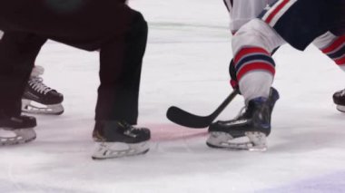 Sopalı oyuncular, lig şampiyonluğu maçında hakimin buz pateni sahasında yürümesini bekliyor.