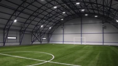 Çağdaş spor arenasında kemer şeklinde çatısı olan yeşil yapay çimlerle kaplı büyük boş bir futbol sahası.