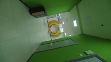 Çağdaş çocuk gelişim merkezi kamerasında yeşil duvarları ve parlak daire dekoru olan boş koridor dönüyor