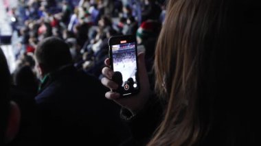 KAZAN, TATARSTAN RUSSIA - 15 Temmuz 2021: Kadın spor taraftarı 15 Temmuz 'da Kazan' da çağdaş stadyumun yakın görüş tribününde cep telefonuyla buz arenasında hokey maçı çekiyor