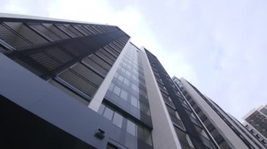 Bulutlu bir günde, yeni bölgede fütüristik cam cepheli, çok katlı bir apartman.