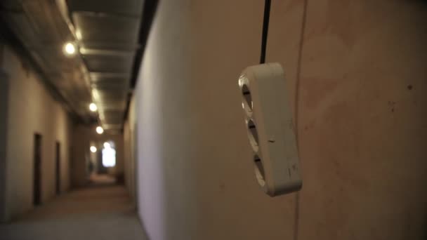 拡張マルチソケットは 建設現場で電球と空の地下廊下の灰色の壁の近くにハングアップします近いビュー — ストック動画