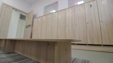 Boş soyunma odası ahşap banklar ve içinde çizgi film resimleri olan küçük dolaplar restore edilmiş anaokulu lobisinde.