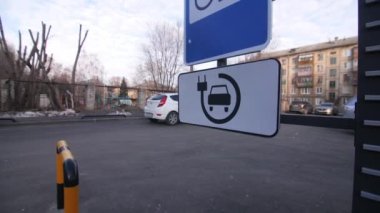 Şehir caddesinde elektrikli araç şarj istasyonu tabelası ve iş merkezindeki engelli yolcular için asansör kapatma
