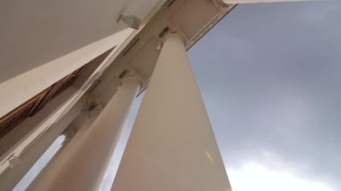 Şehir caddesindeki tiyatro binasının girişindeki beyaz klasik sütunlar bulutlu gökyüzünün altında yakın plan alçak açılı çekim