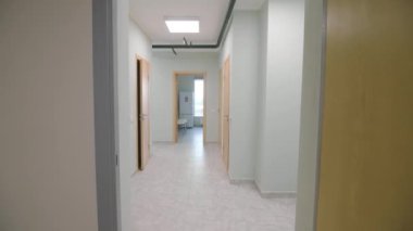 Çağdaş kamu binasındaki ofislere açılan açık kapılarla aydınlık bir koridor. Sosyal Hizmetler Merkezi