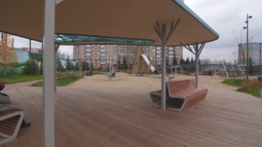 Bulutlu bir günde, büyük çocukların oyun parkının yanındaki bankları olan şık bir çardak.