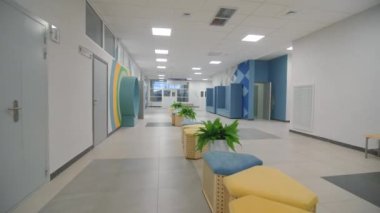 Anaokulu binasının boş koridorunda yumuşak puf ve bitkiler. Okulun iç tasarımında parlak renkler