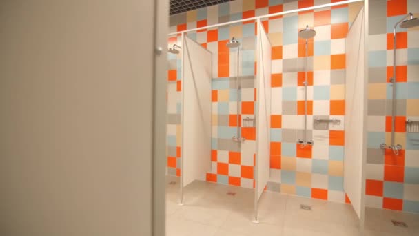 当代体育中心空旷的公共浴室 墙壁上有分隔的小木屋和五颜六色的瓷砖图案 — 图库视频影像