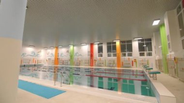 Modern spor kompleksinde eğitim ve dinlenme amaçlı duvarlarda temiz su ve renkli resimler olan boş yüzme havuzu