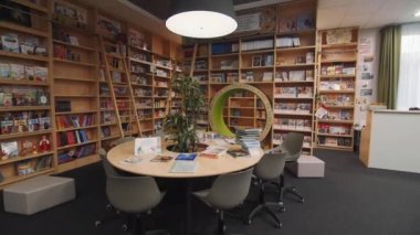 KAZAN, TATARSTAN RUSSIA - Ekim 05 2021: Yeni ahşap kitaplıklar ve ev bitkileriyle dolu yuvarlak masa okuma salonu. Edebiyat ve bilgiler Kazan 'da Ekim 05' te