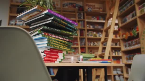 カザフスタン タタールスタンロシア 2021年10月5日 カザンで10月5日に子供のためのきちんとした図書館読書ホールで本棚に対する木製のテーブルの上にロシアのおとぎ話の本の高スタック — ストック動画