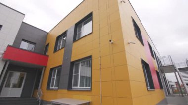 Kasvetli bir günde şehir merkezinde sarı cepheli ve güvenlik merdivenli çocuk geliştirme merkezi.