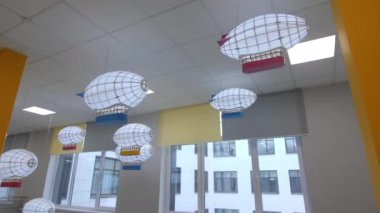 Güzel oyuncak zeplinler yenilenmiş okul binasının boş koridorunda tavanda asılı duruyor. Çocuklar için dekoratif öğeler